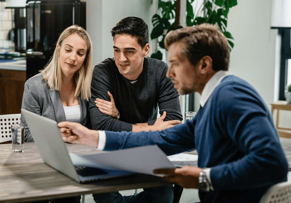 young-couple-real-estate-agent-using-laptop-while-going-through-housing-plan-meeting 1 young-couple-real-estate-agent-using-laptop-while-going-through-housing-plan-meeting 1